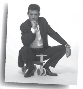 Stefán Karl sitting on a tiny toy bike for toddlers