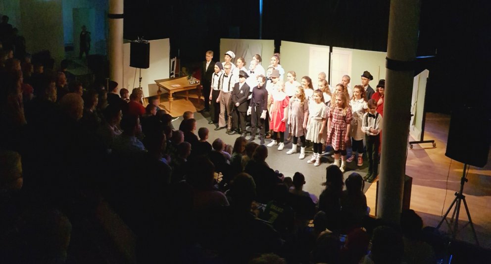 Nemendur sjöunda bekkjar á sviði og fullt hús.