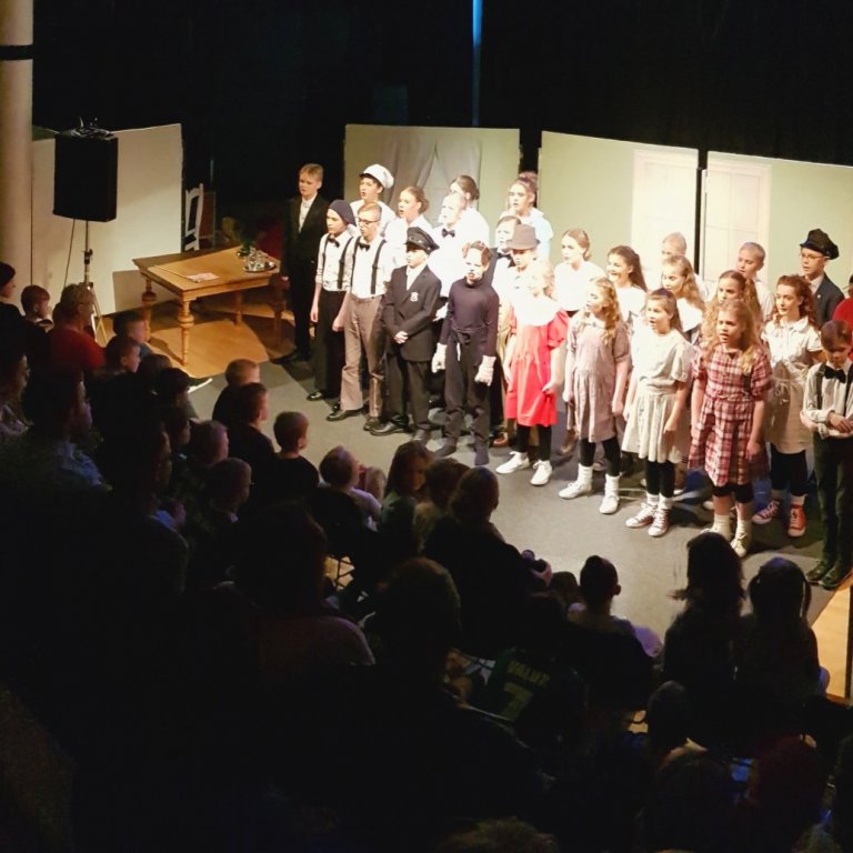 Nemendur sjöunda bekkjar á sviði og fullt hús.